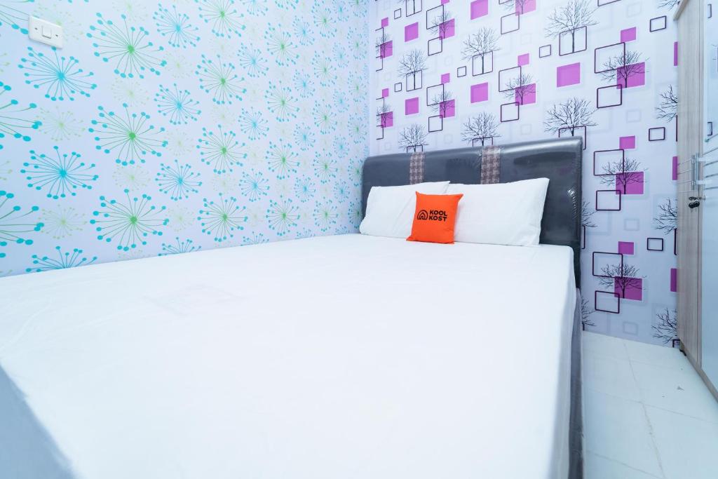 a bedroom with a white bed with blue and pink wallpaper at KoolKost At Menceng Raya - Minimum Stay 30 Nights in Jakarta
