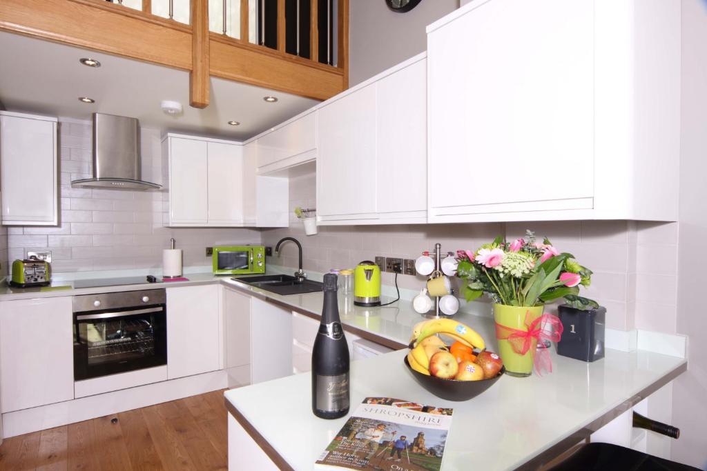 a kitchen with white cabinets and a counter with a bowl of fruit at Wenlock Studios in Much Wenlock