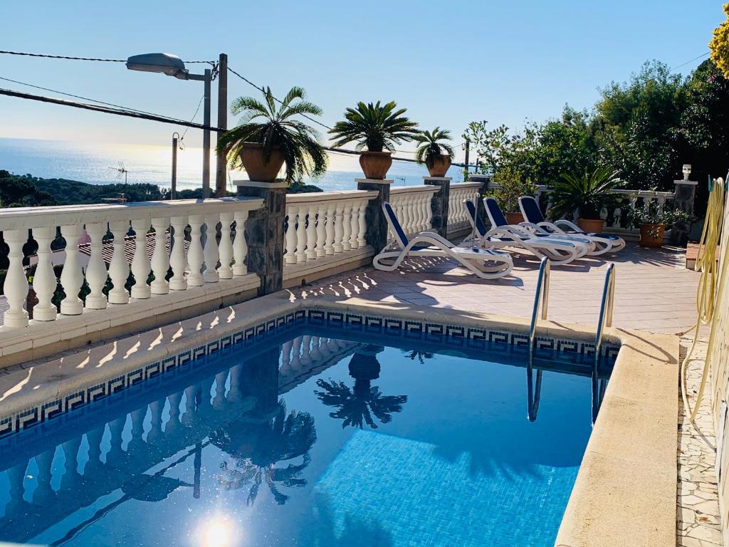 een zwembad met stoelen naast een hek bij Mediterranean Villa Investingspain sea view and pool in Lloret de Mar