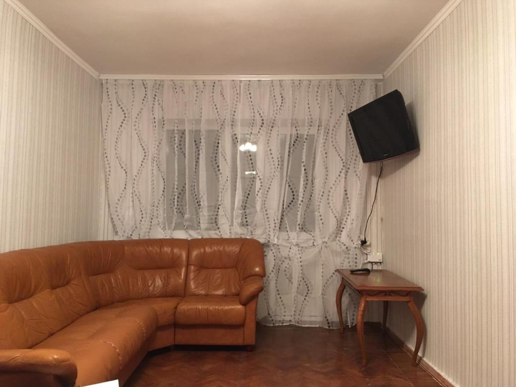 salon z brązową skórzaną kanapą i telewizorem w obiekcie Квартира на Фонтане. w Odessie