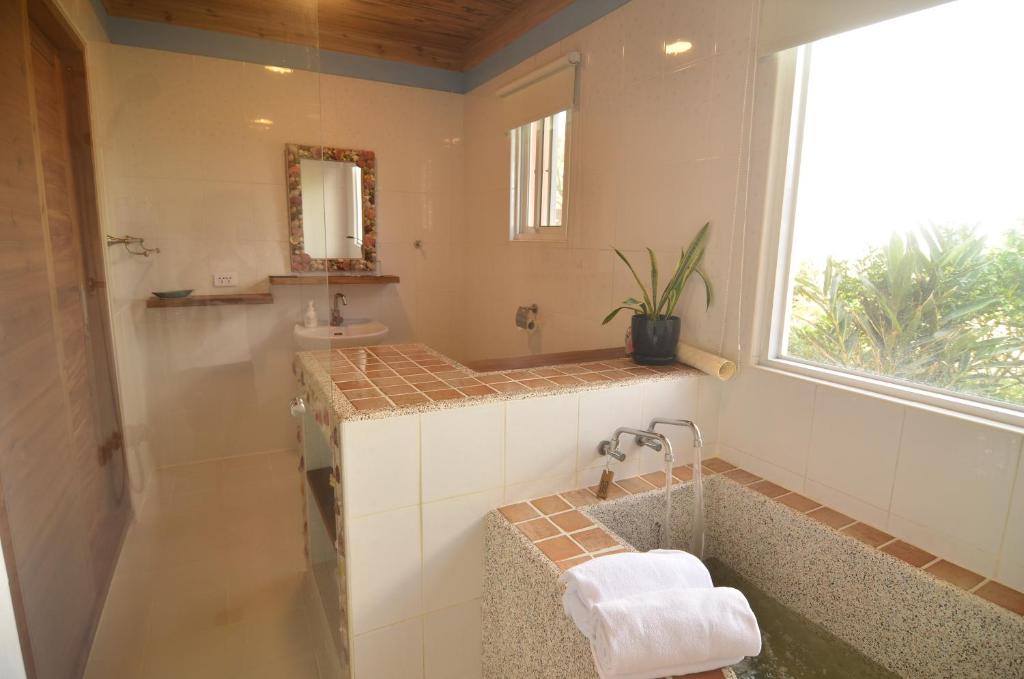 a bathroom with a tub and a sink and a window at Kenting COMIC B&amp;B in Hengchun South Gate