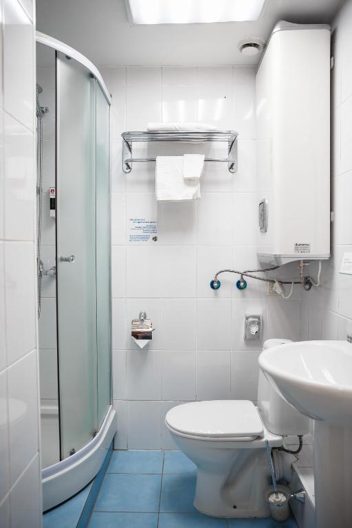 a bathroom with a toilet and a sink and a shower at AZIMUT Hotel Kemerovo in Kemerovo