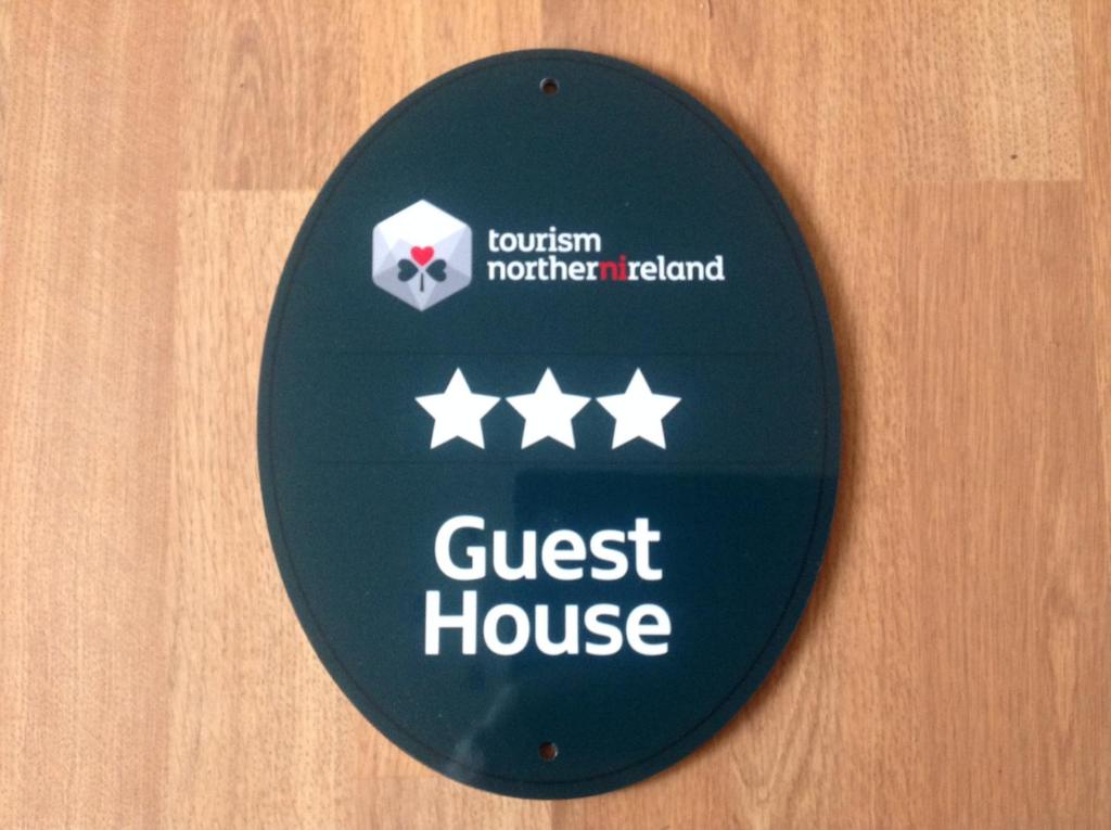 a close up of a guest house sign on a door at Beulah Guest House in Portrush