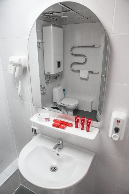 a bathroom with a white sink and a mirror at AZIMUT Hotel Kemerovo in Kemerovo