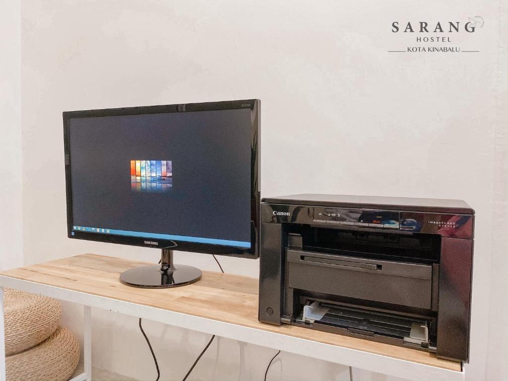 a computer monitor sitting on a table with a printer at Sarang Hostel at City Centre in Kota Kinabalu