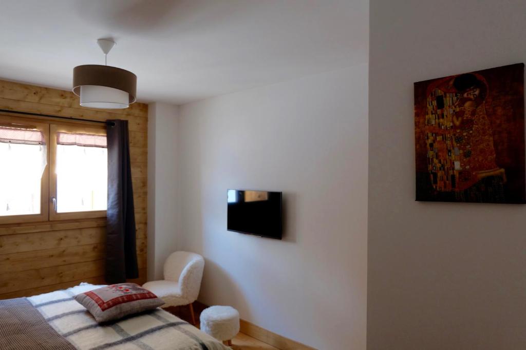 a bedroom with a bed and a chair and a window at Appartement Soleil Blanc Résidence Lodge des neiges in Tignes