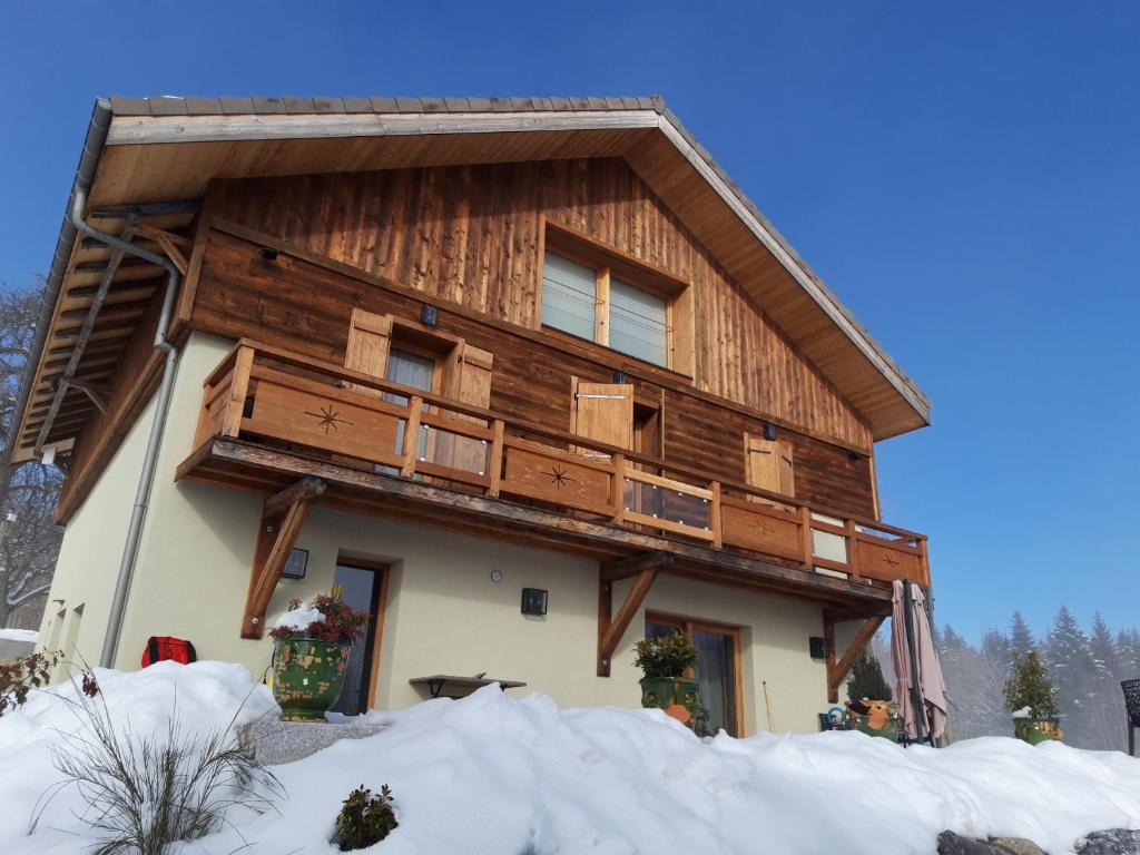 une maison avec une façade en bois dans la neige dans l'établissement Les Chalets de Ludran, à Viuz-en-Sallaz