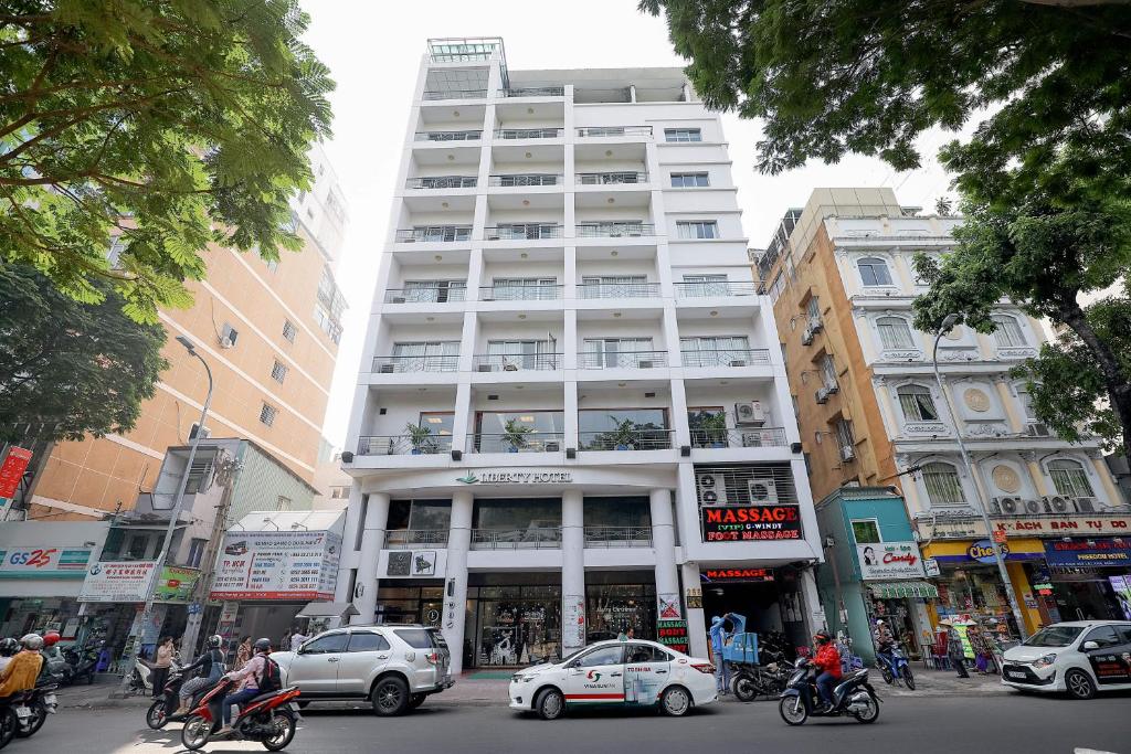 un edificio blanco alto en una calle de la ciudad con coches en Liberty Hotel Saigon Parkview, en Ho Chi Minh