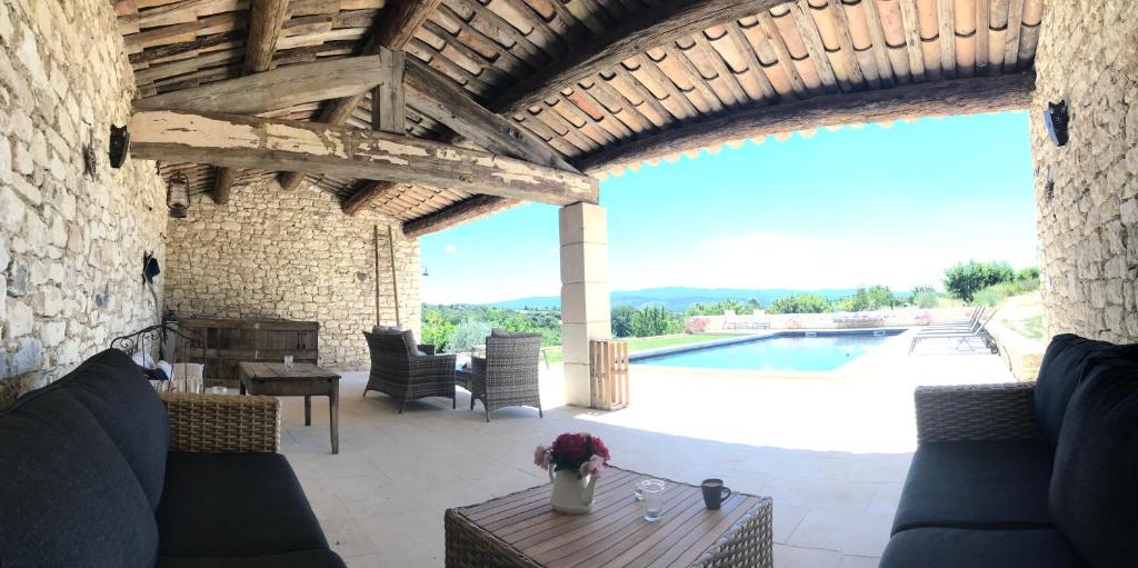eine Terrasse mit Sofas, einem Tisch und einem Pool in der Unterkunft Le Mas Silvestre in Saint-Saturnin-dʼApt