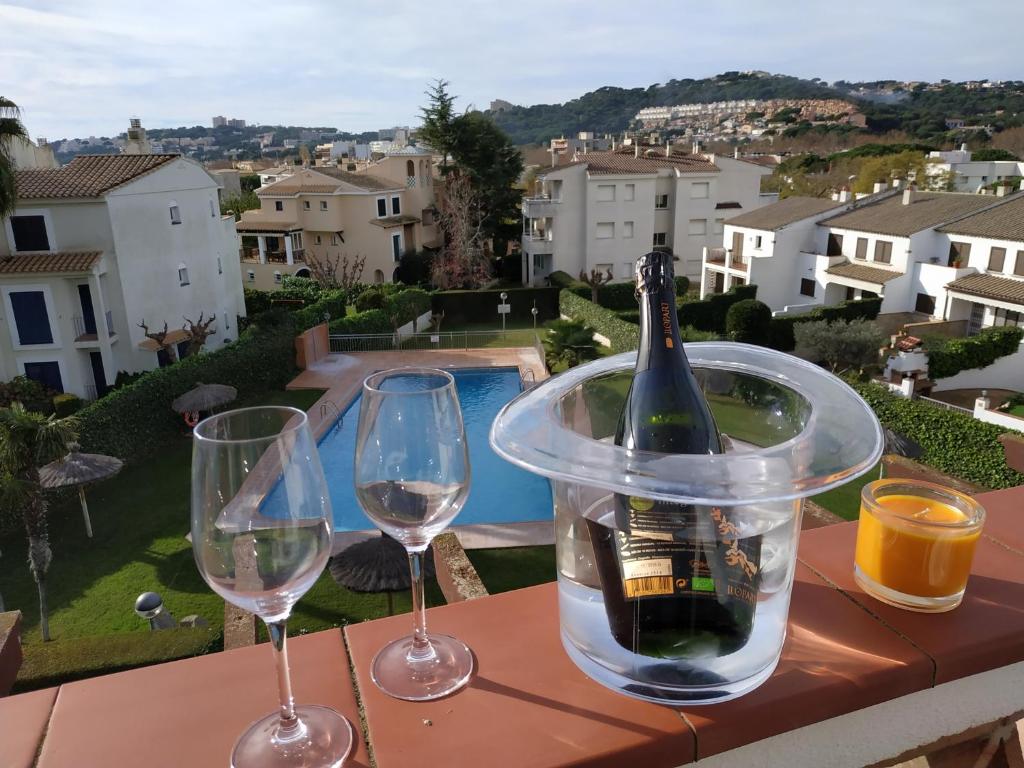 a bottle of wine in a container on a table with two glasses at Apartamento S'Agaró Fagoi in S'Agaro
