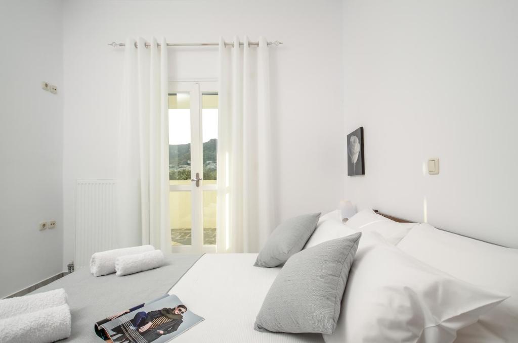 een witte slaapkamer met een bed en een raam bij Bernie House in Mélanes