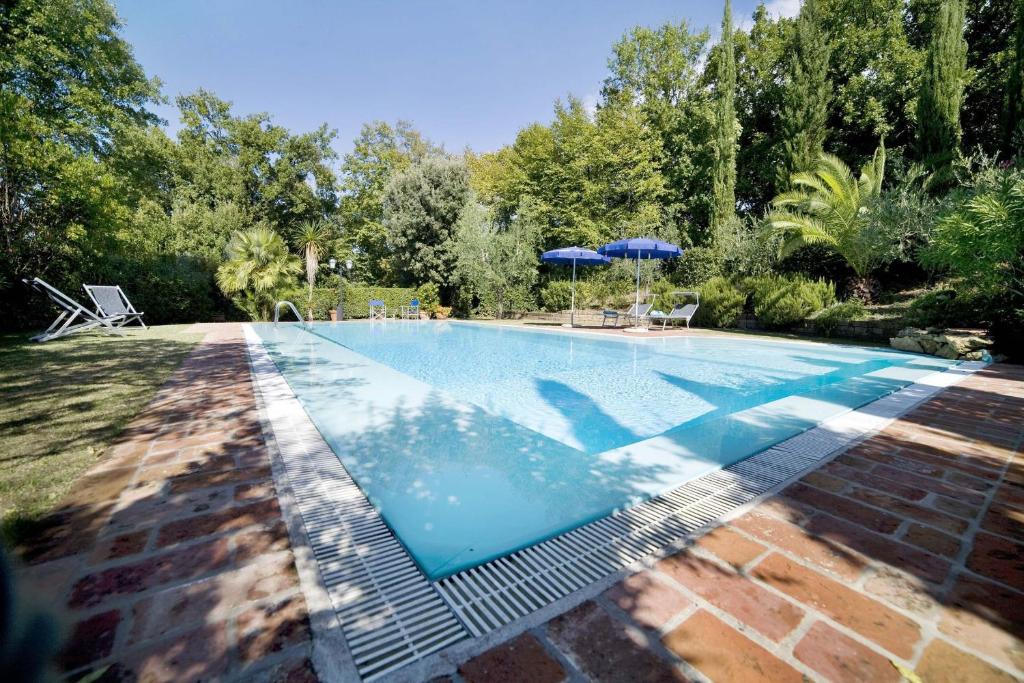 a swimming pool in a garden with an umbrella at Villa La Capinera in Montopoli in Val dʼArno