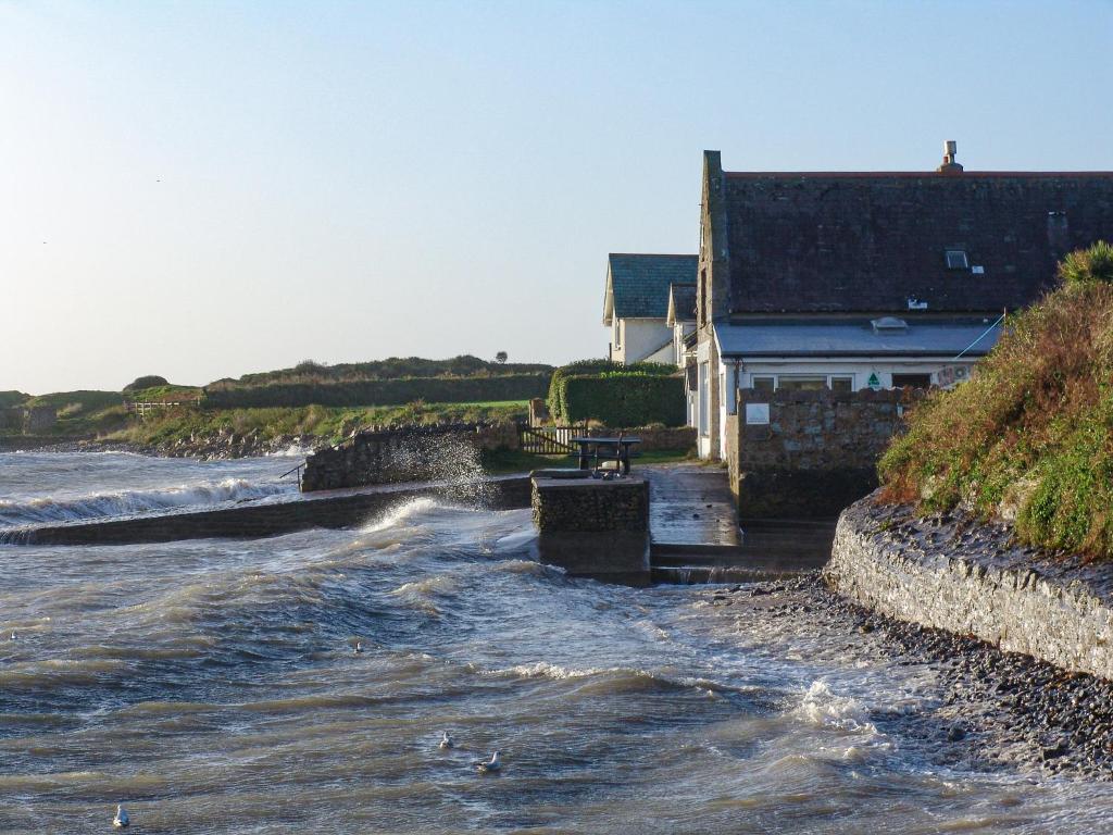 a house on the shore of a river with waves at YHA Port Eynon in Port-Eynon