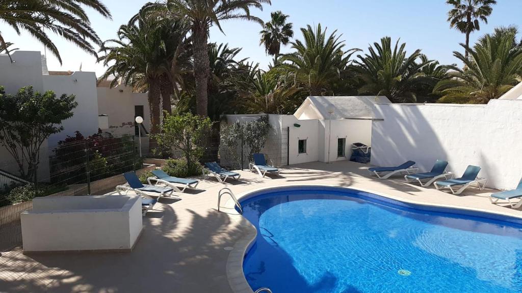a villa with a swimming pool and palm trees at Workation - La Casita de Elsi y Fran in Costa Calma