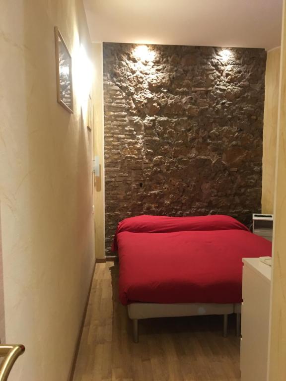 een rood bed in een kamer met een stenen muur bij B&B In Piazza in Rome