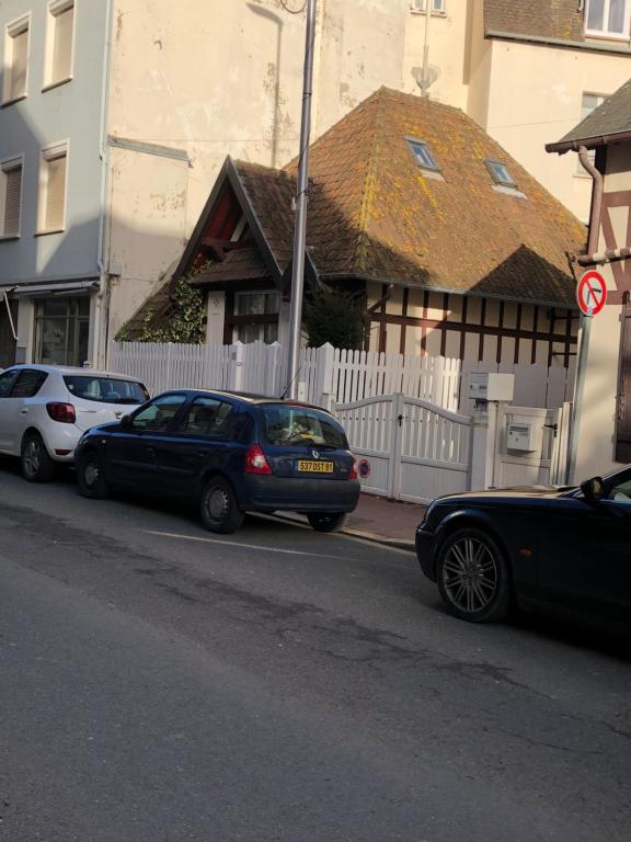 Deux voitures garées sur le côté d'une rue dans l'établissement Charmante maison cœur de ville La Gare des vacances, à Deauville