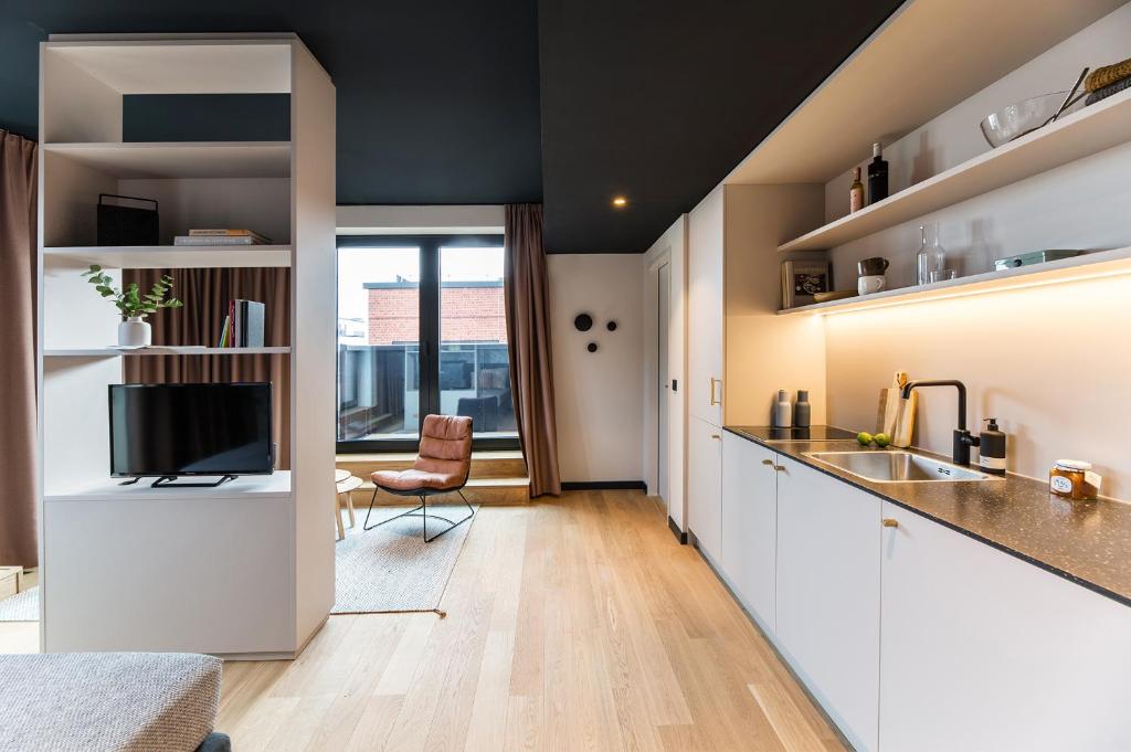 a kitchen with white cabinets and a sink and a tv at ipartment Hamburg HafenCity in Hamburg