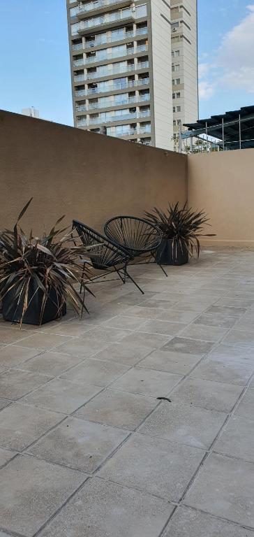 Habitania Bahia - Cochera opcional في باهيا بلانكا: كرسيان يجلسون بجوار جدار بالنباتات