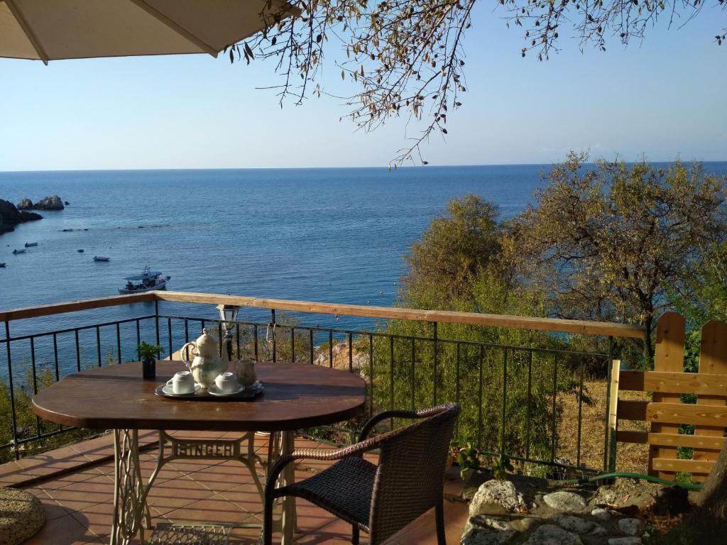 un tavolo e delle sedie su un balcone con vista sull'oceano di Ostria a Ayios Nikitas