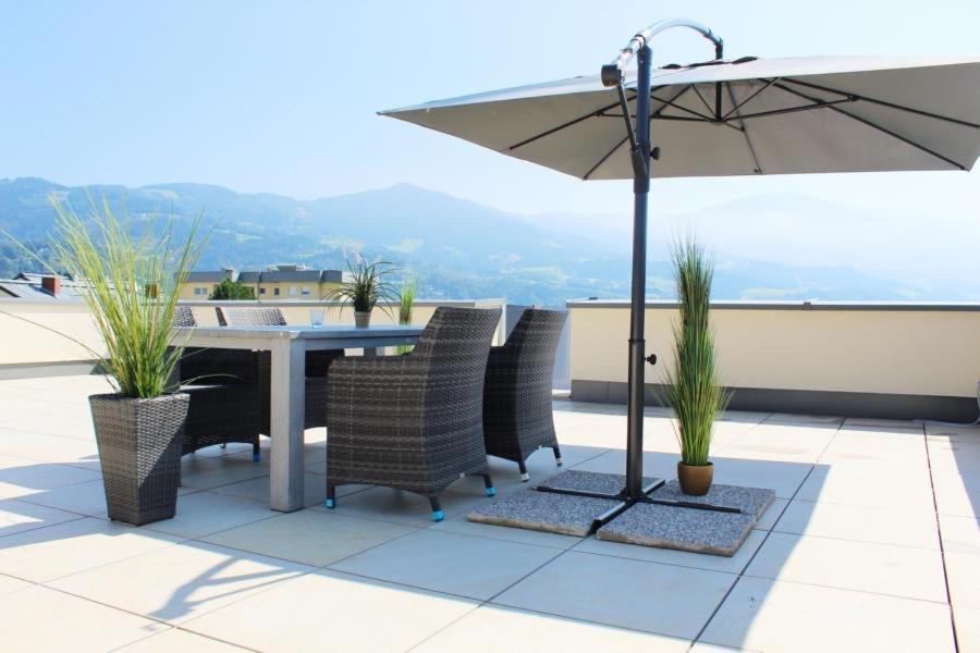 stół i krzesła z parasolem na dachu w obiekcie Dachterrassen Appartement Monte Lupo w mieście Wolfsberg