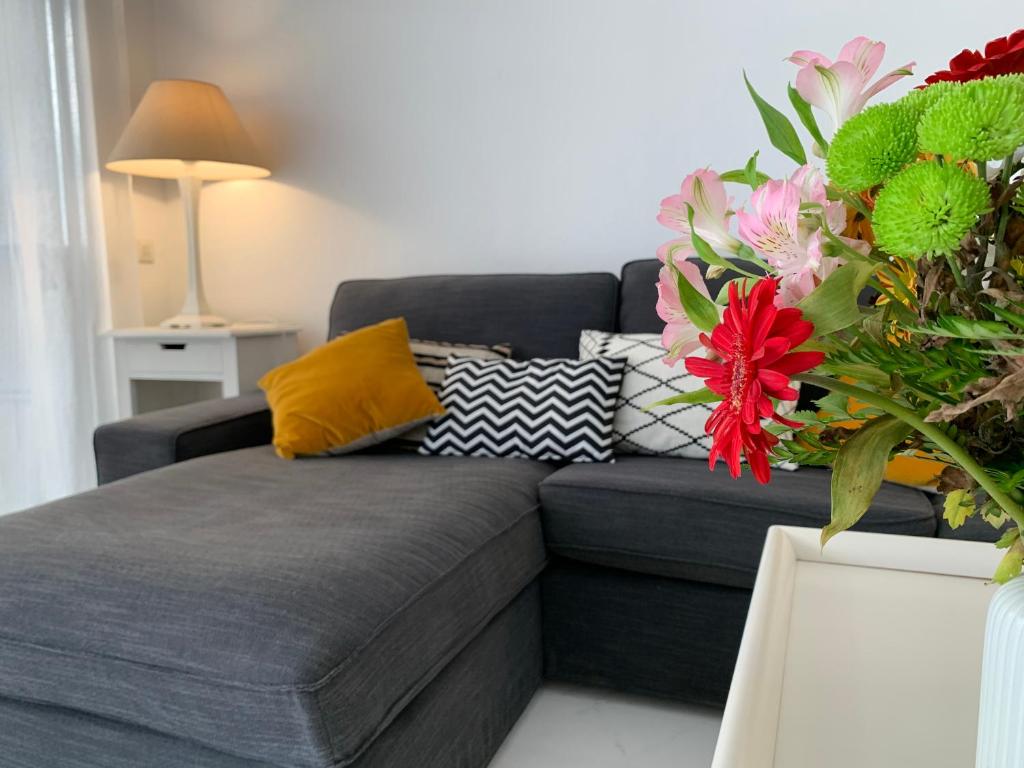 uma sala de estar com um sofá cinzento com almofadas coloridas em Jardines del Mar Beach - WiFi 539 em Marbella
