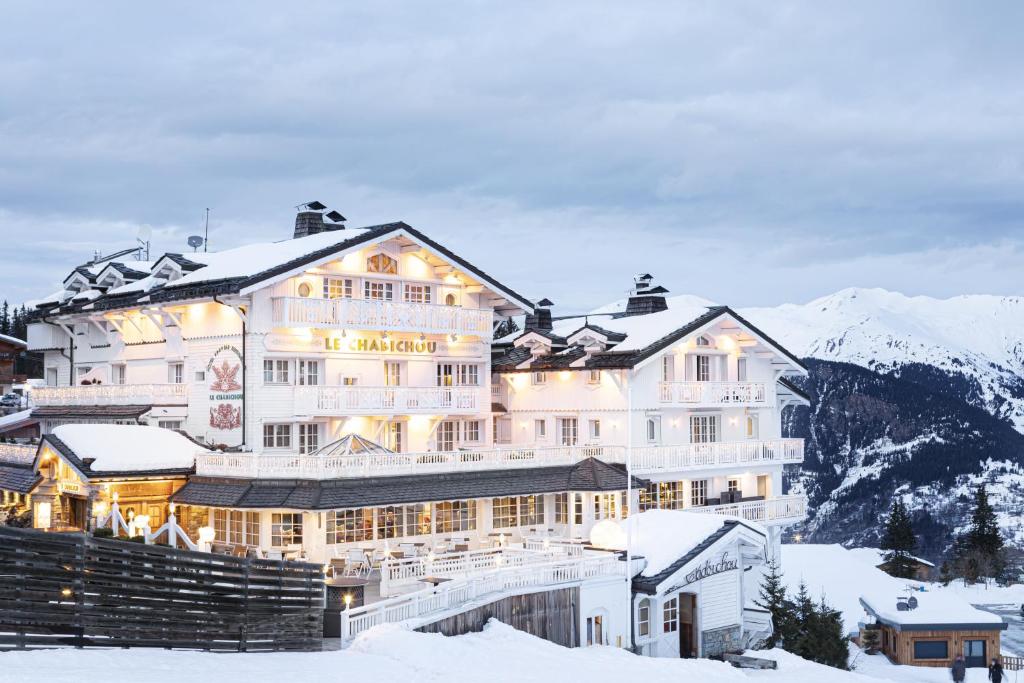 a large white building in the snow with mountains at Hotel Le Chabichou in Courchevel