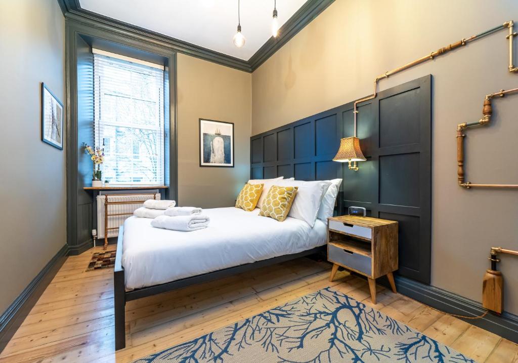 um quarto com uma cama grande e uma cabeceira azul em The Waverley Park Residence em Edimburgo