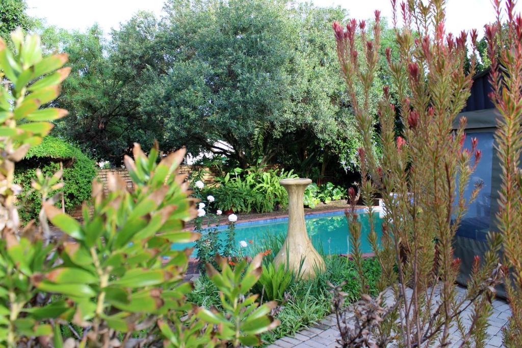 a garden with a large vase sitting next to a pool at Ukarimu Guest House in Klerksdorp