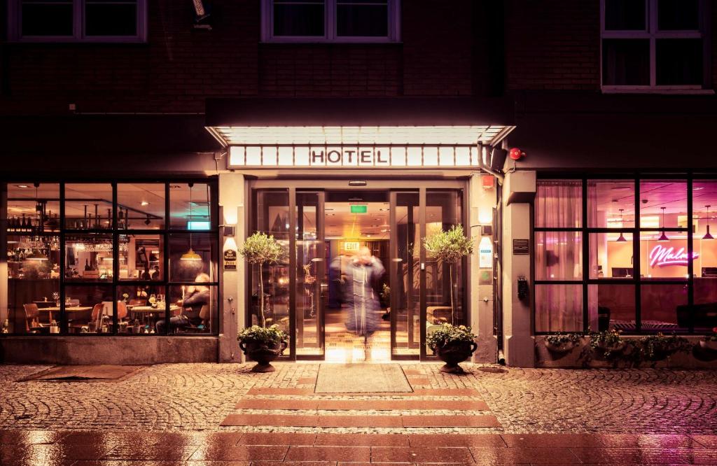 a woman walking out of a hotel at night at Best Western Plus Hotel Noble House in Malmö