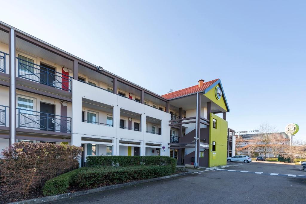 un immeuble d'appartements avec un jaune et un blanc dans l'établissement B&B HOTEL Auxerre Bourgogne, à Monéteau