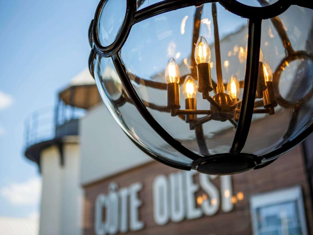 un primer plano de una lámpara de araña con un faro en el fondo en Côte Ouest Hôtel Thalasso & Spa Les Sables d'Olonne - MGallery, en Les Sables-dʼOlonne