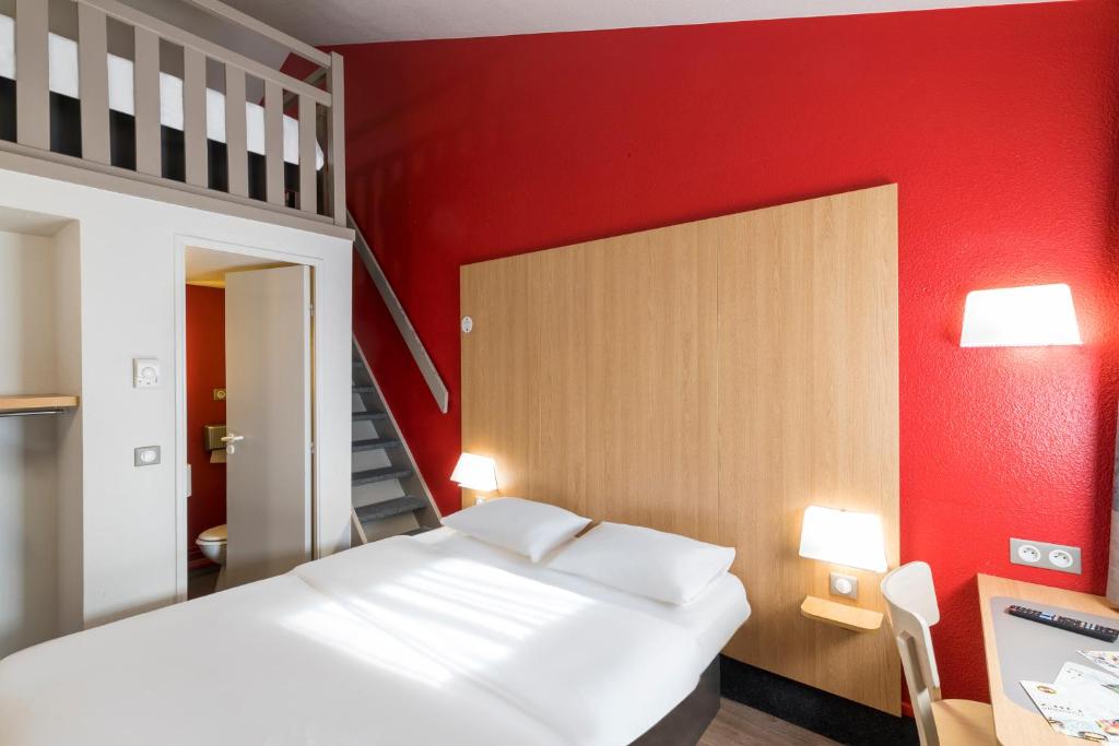 a bedroom with a white bed and a red wall at B&B HOTEL Auxerre Bourgogne in Monéteau