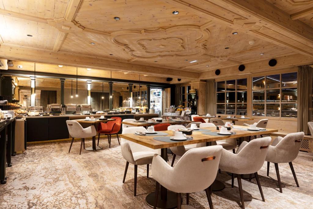 a restaurant with wooden ceilings and tables and chairs at Hotel Le Chabichou in Courchevel