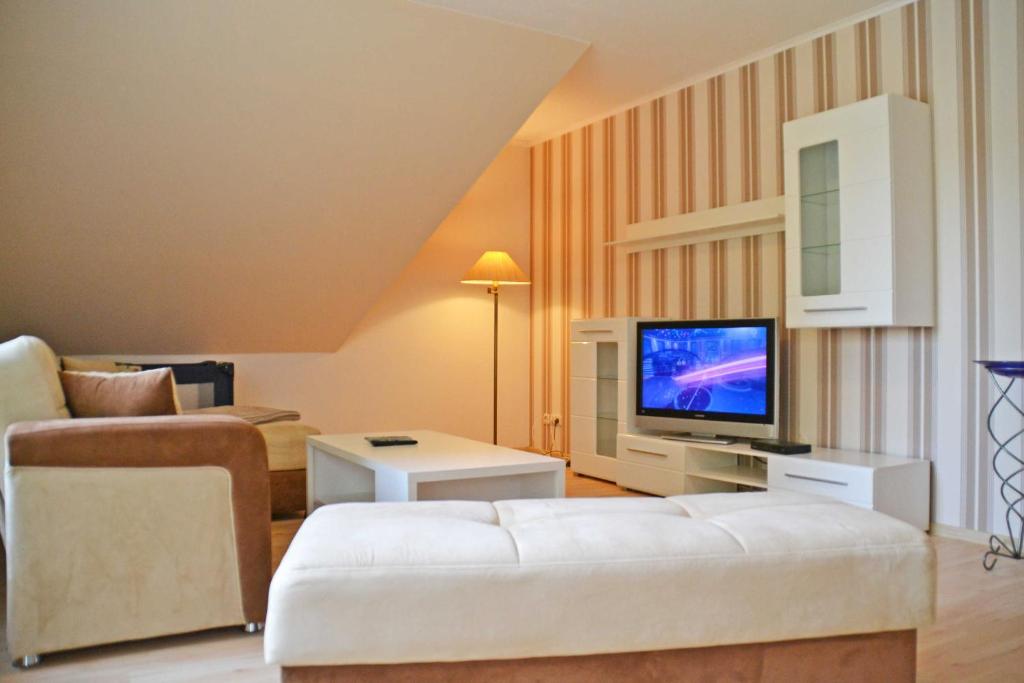 een woonkamer met een witte bank en een televisie bij Ferienwohnung Wiesenblick in Kerkwitz