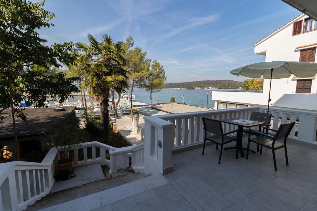 a balcony with a table and chairs and a view of the water at Apartman Hrabrić 2 in Njivice