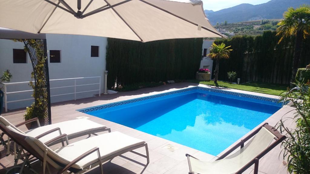 a swimming pool with two chairs and an umbrella at Chalet AIRAM in Monachil