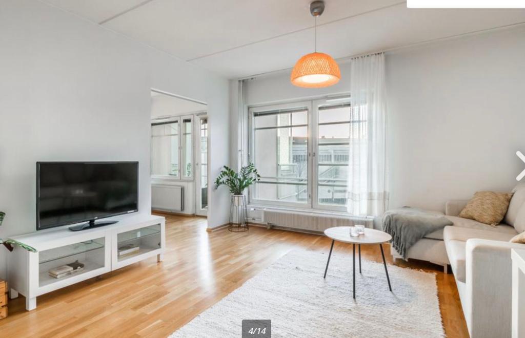 a living room with a couch and a tv at Scandinavian design heart City Center Runeberginkatu in Helsinki