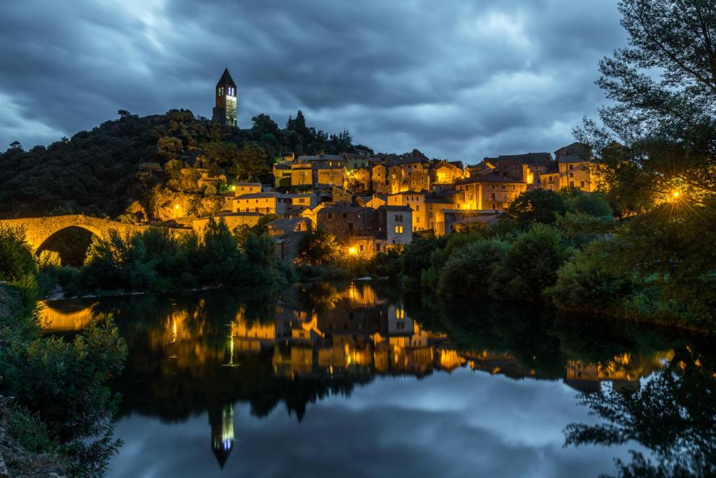 een stad op een heuvel naast een rivier in de nacht bij Ecole Olargues - Teritoria in Olargues