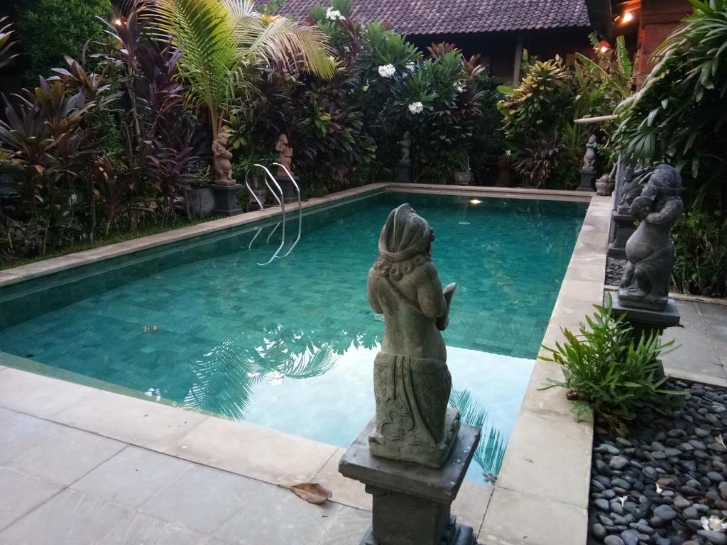 una pequeña piscina con estatuas en el agua en The Sari Bungalows, en Pemuteran