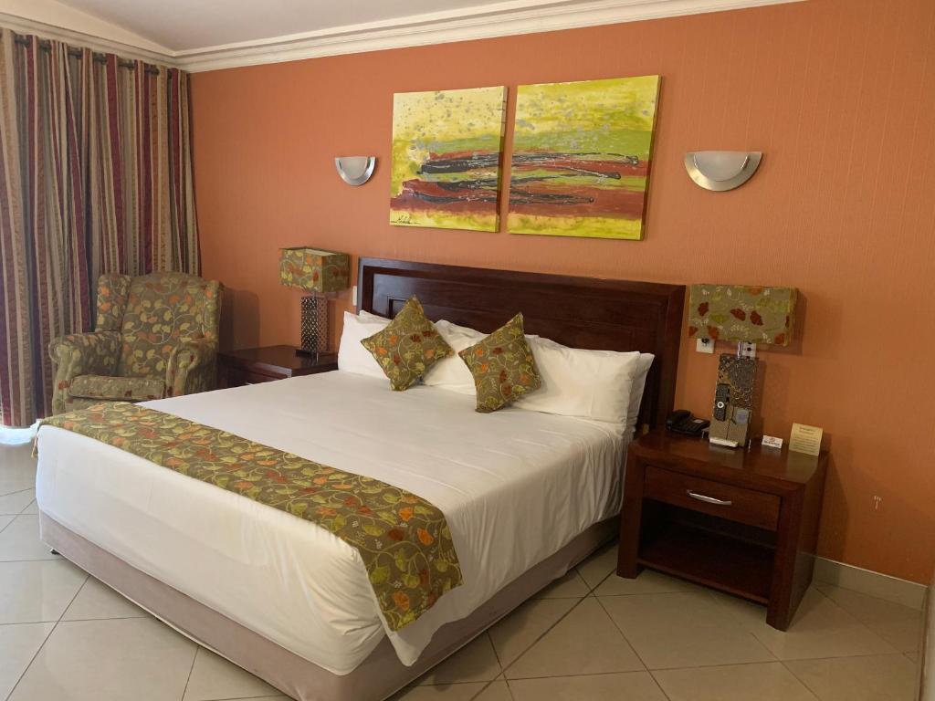 Pokój hotelowy z łóżkiem i krzesłem w obiekcie Royal Hotel w mieście Polokwane