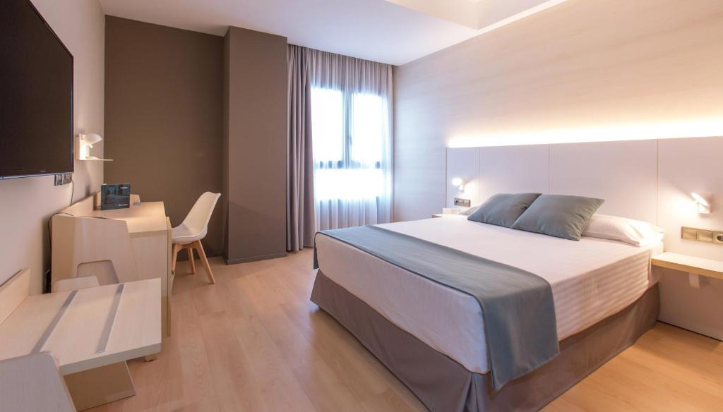 - une chambre avec un lit, un bureau et une télévision dans l'établissement Hotel Olympia Valencia, à Alboraya