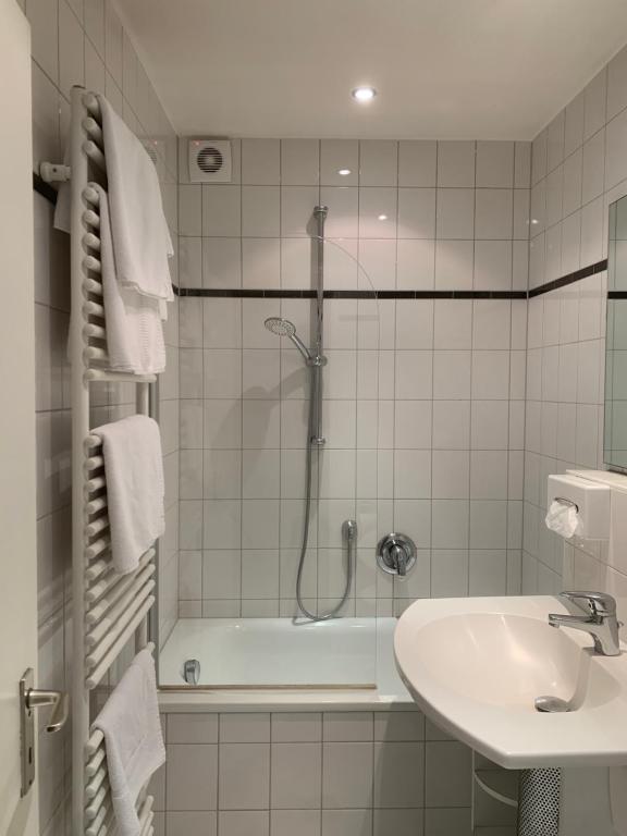 La salle de bains est pourvue d'une douche, d'un lavabo et d'une baignoire. dans l'établissement Hotel Mondial Comfort - Frankfurt City Centre, à Francfort-sur-le-Main