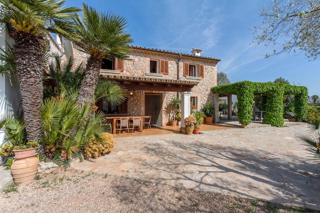 a villa with a palm tree and a patio at Ca Na Margalida in Port de Pollensa