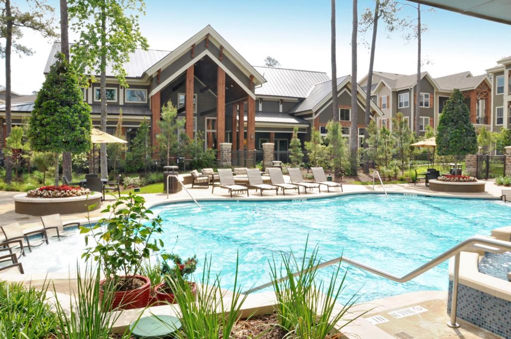 een zwembad met stoelen en een gebouw bij Resort Style Apartment/Home - The Woodlands in The Woodlands