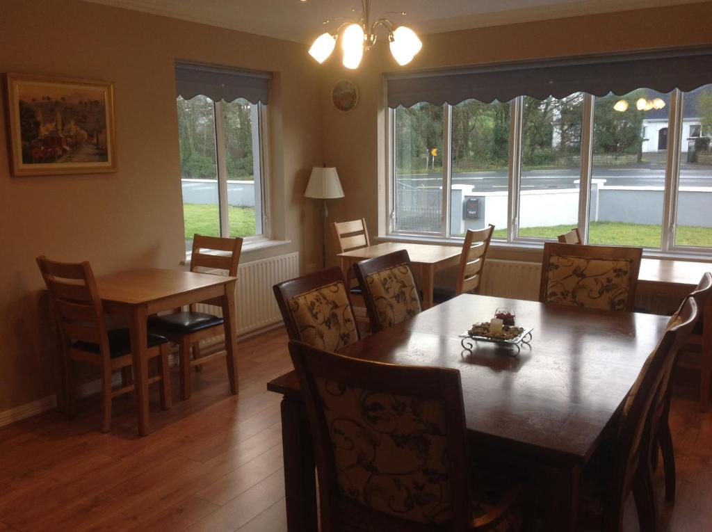 uma sala de jantar com mesa, cadeiras e janelas em Lilac Manor em Sligo