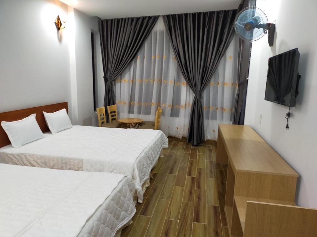 a hotel room with two beds and a television at Hotel Hiệp Thành in Tuy Hoa