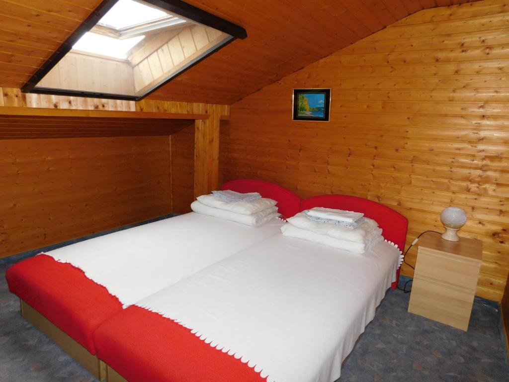 a bedroom with a red bed with a window at Gárdonyi faház 4 fő részére in Gárdony