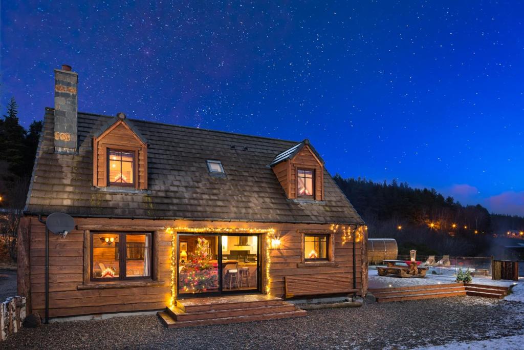 a log cabin with lights on it at night at Snowy River Lodge in Aviemore