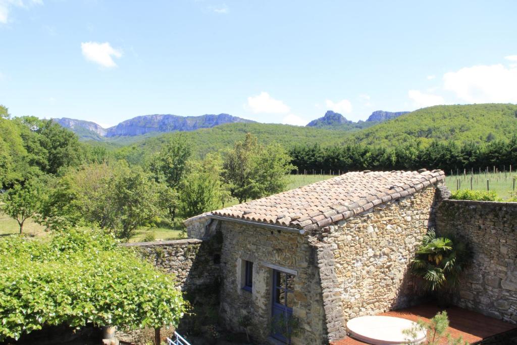 un bâtiment en pierre avec une montagne en arrière-plan dans l'établissement Le Mas Bellane, à Salettes