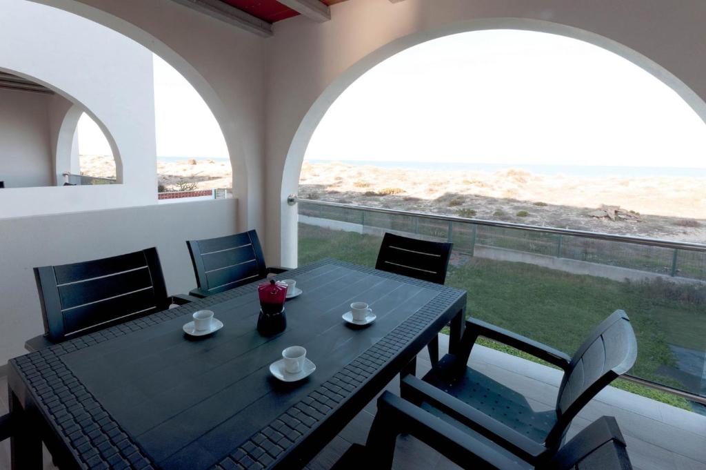 a dining table and chairs in a room with two windows at Vistamar 1 in Oliva